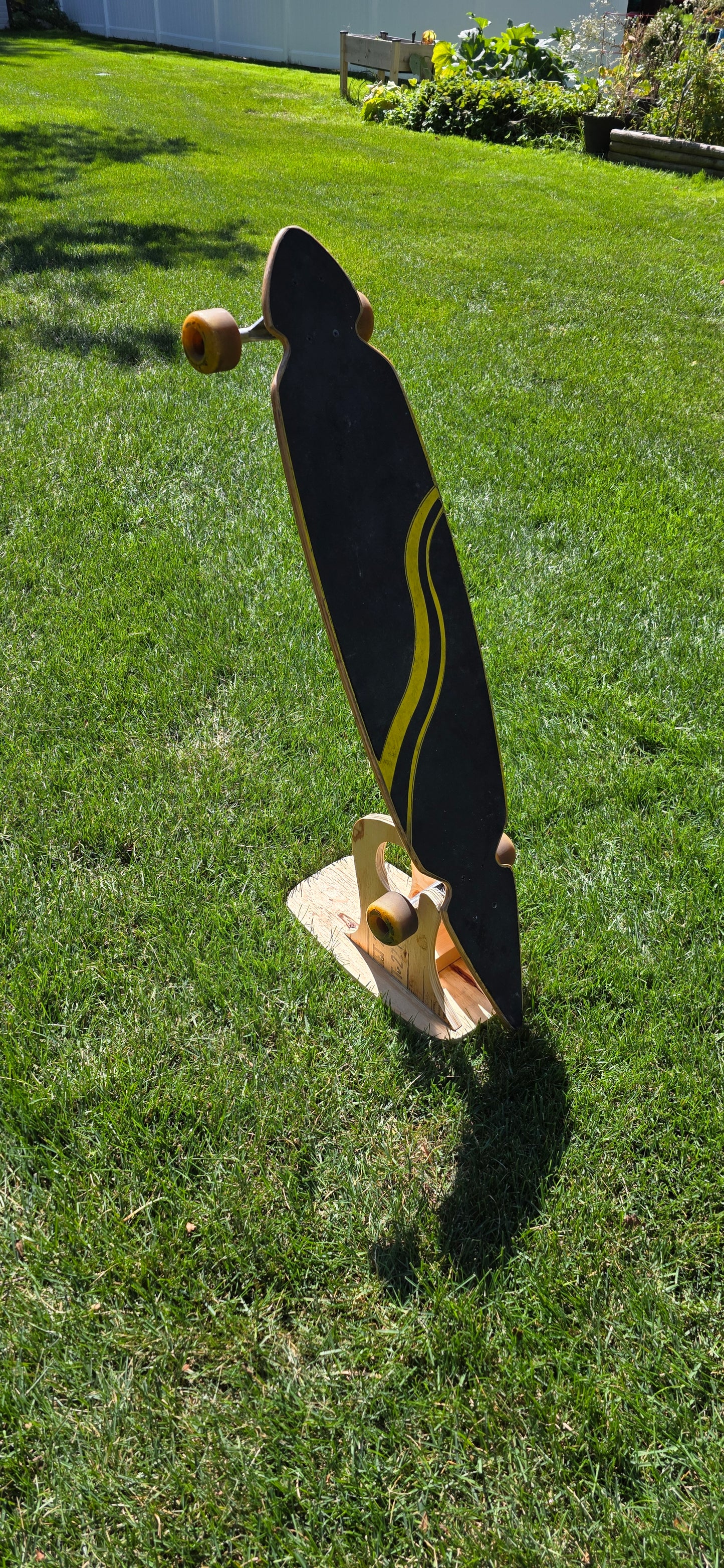 Construction Claw holding a longboard outside, displaying topside