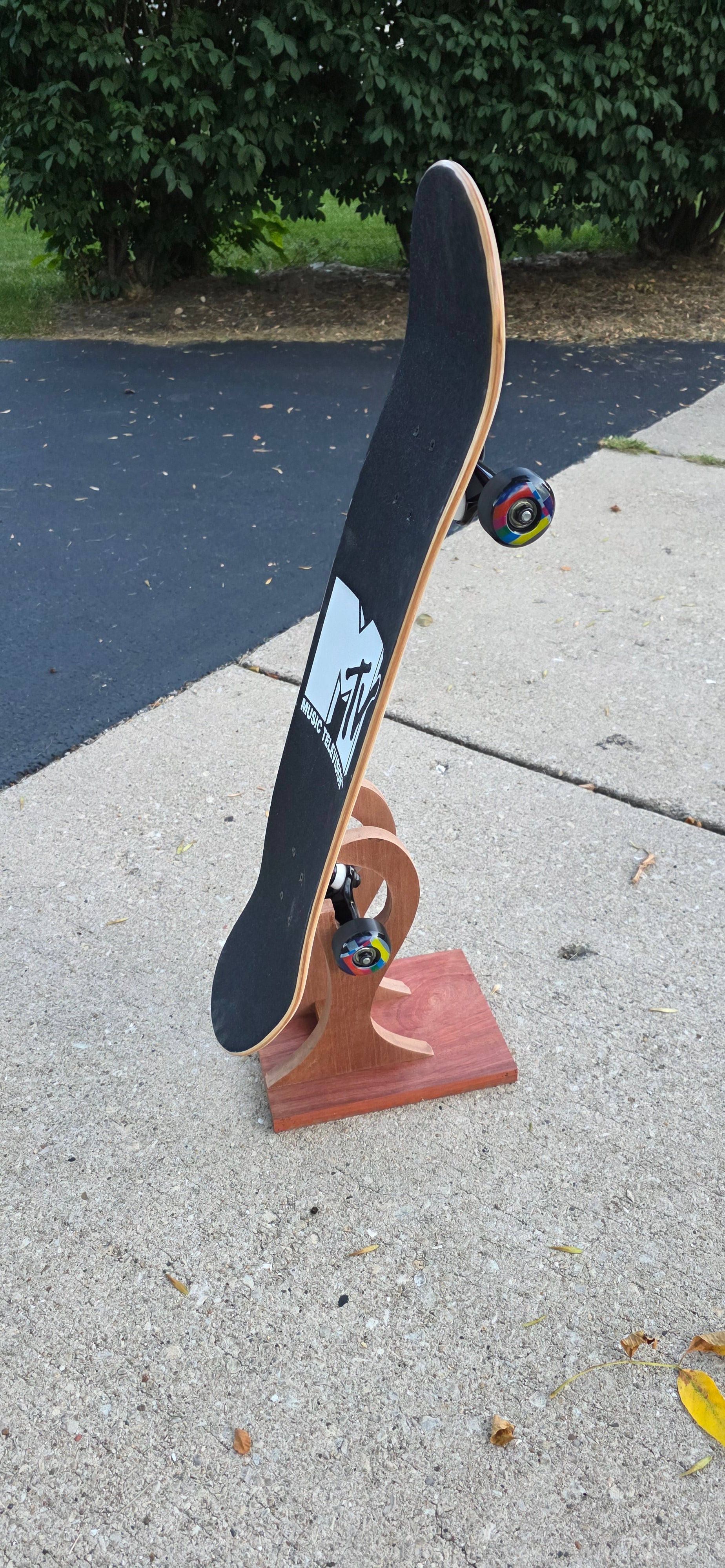 Little Claw holding a regular skateboard outside, displaying topside