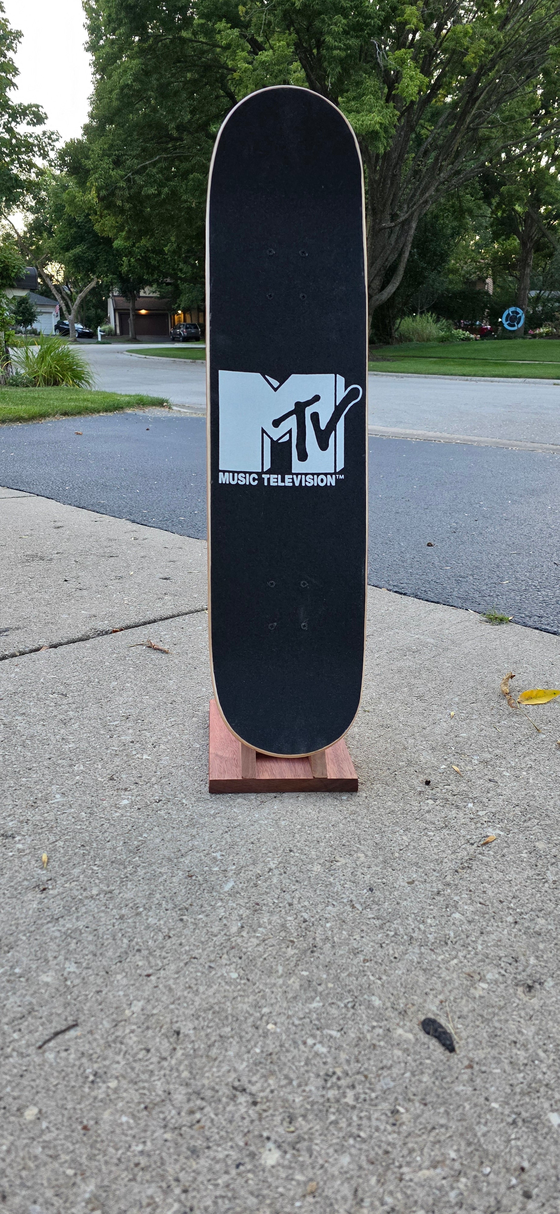 Little Claw holding a regular skateboard outside, displaying topside