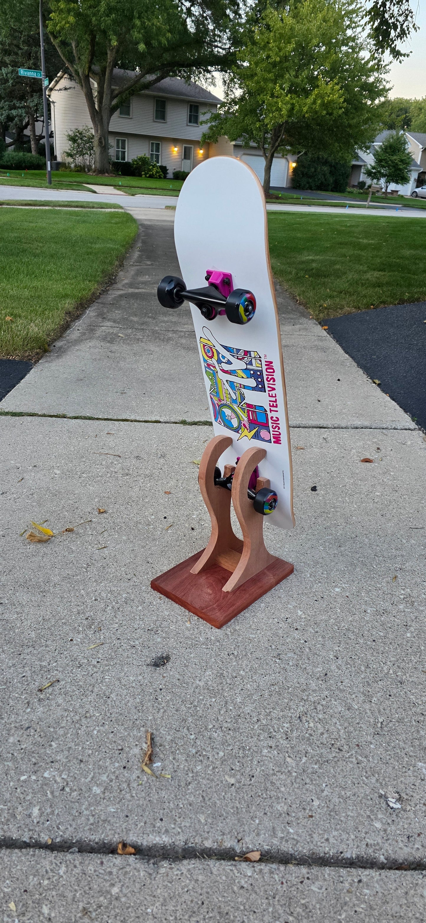 Little Claw holding a regular skateboard outside, displaying bottomside