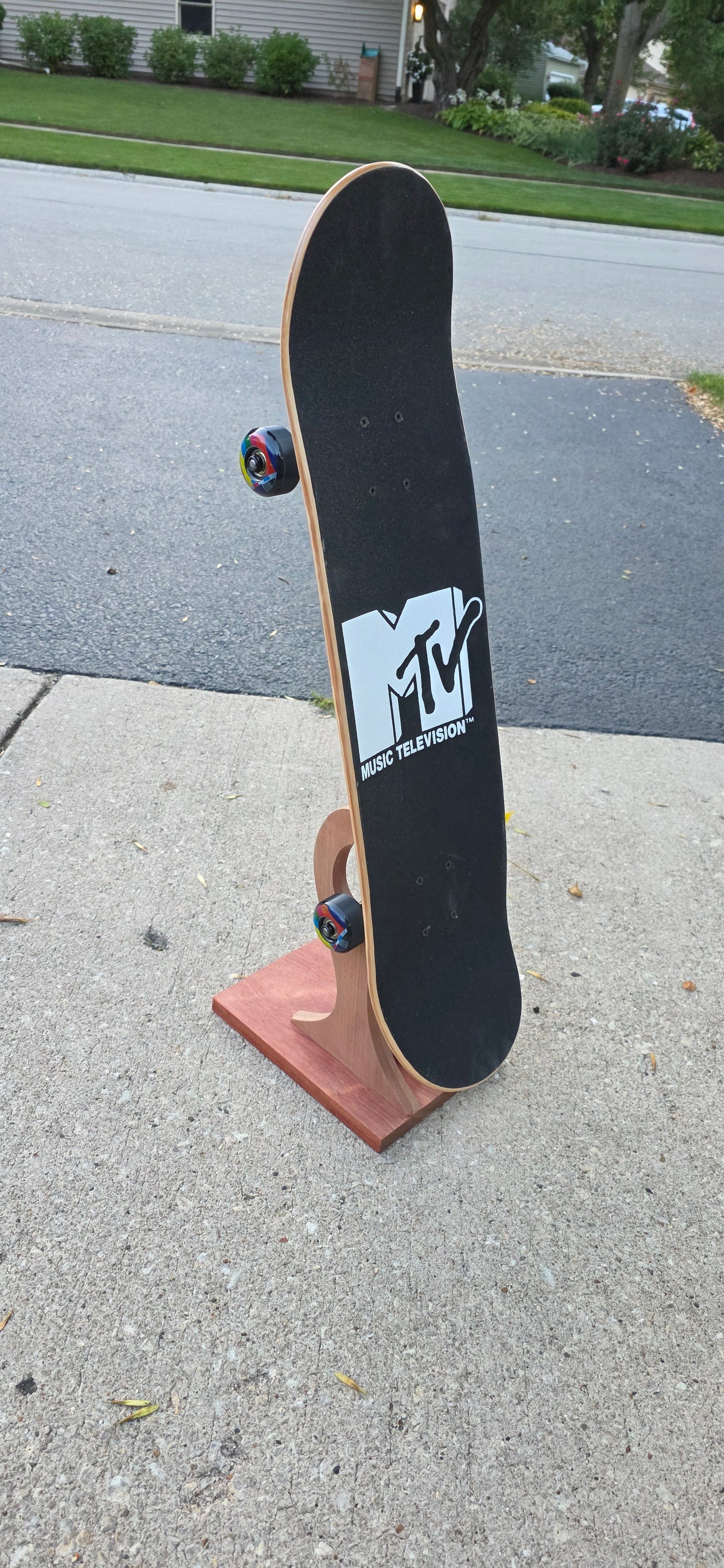Little Claw holding a regular skateboard outside, displaying topside