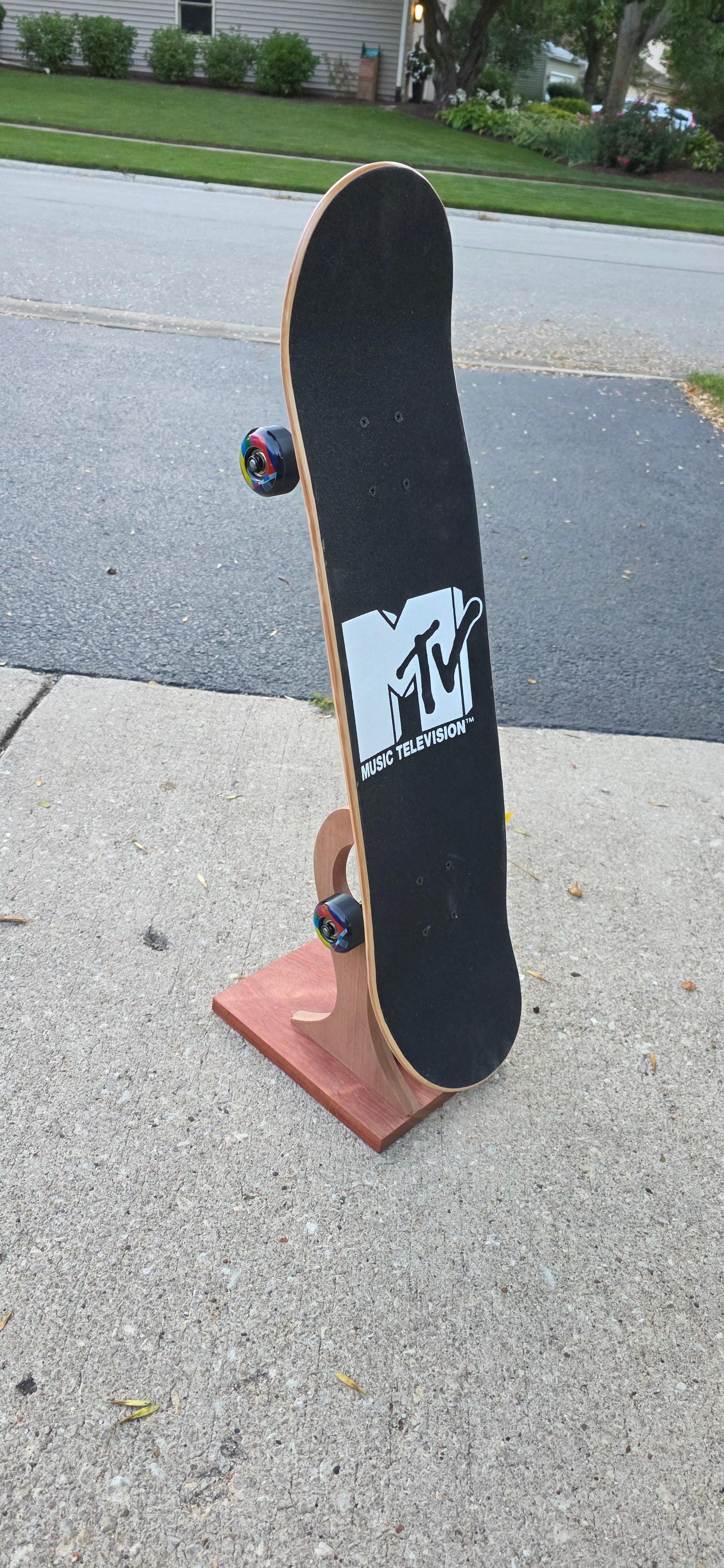 Little Claw holding a regular skateboard outside, displaying topside